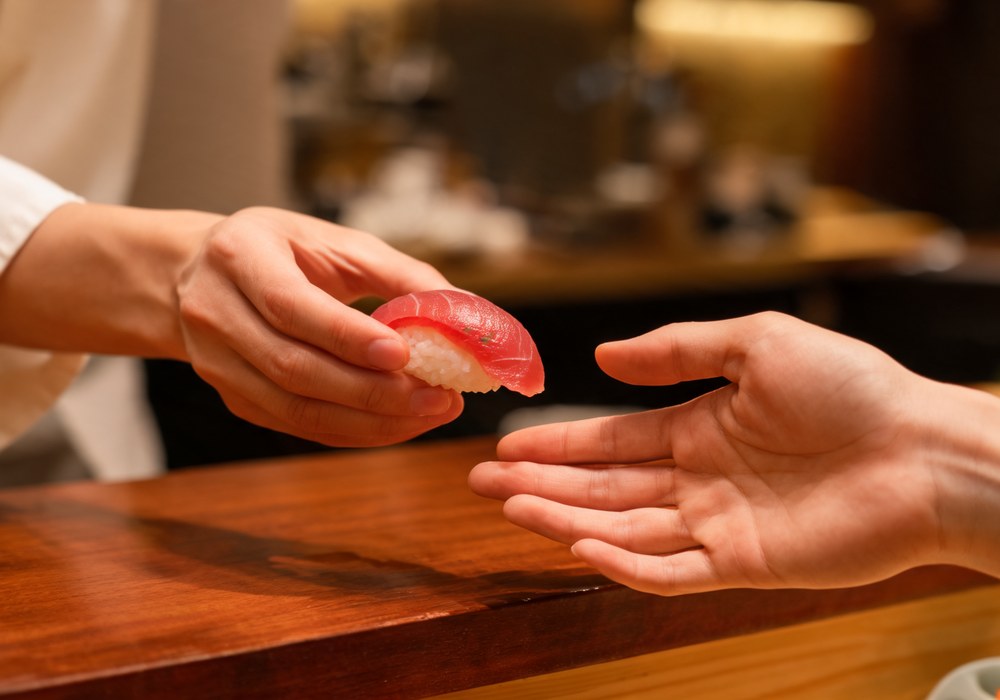 A single piece of nigiri handed across the counter